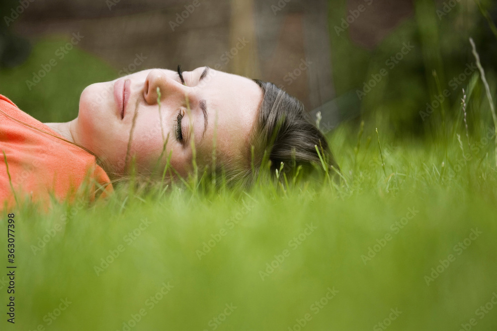 Girl lying on grass with her eyes closed