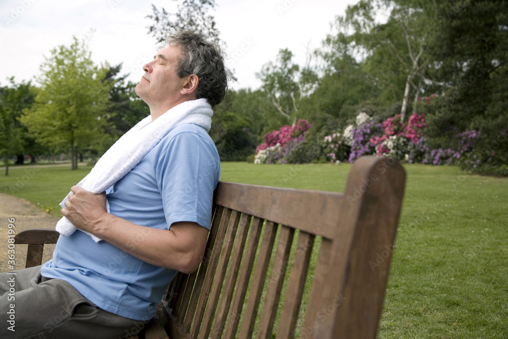Senior man with towel around his neck, sitting on bench with his eyes closed Senior man with towel around his neck, sitting on bench with his eyes closed