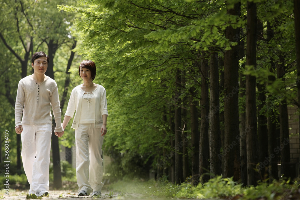 Man and woman holding hands while walking in the park Man and woman holding hands while walking in the park