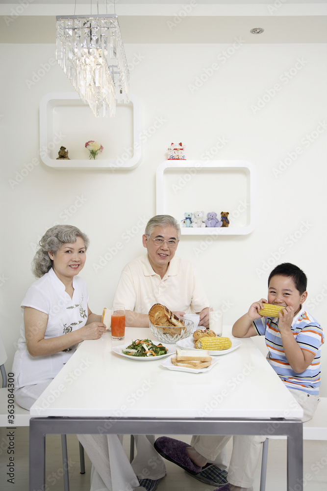 Boy having breakfast with senior man and senior woman