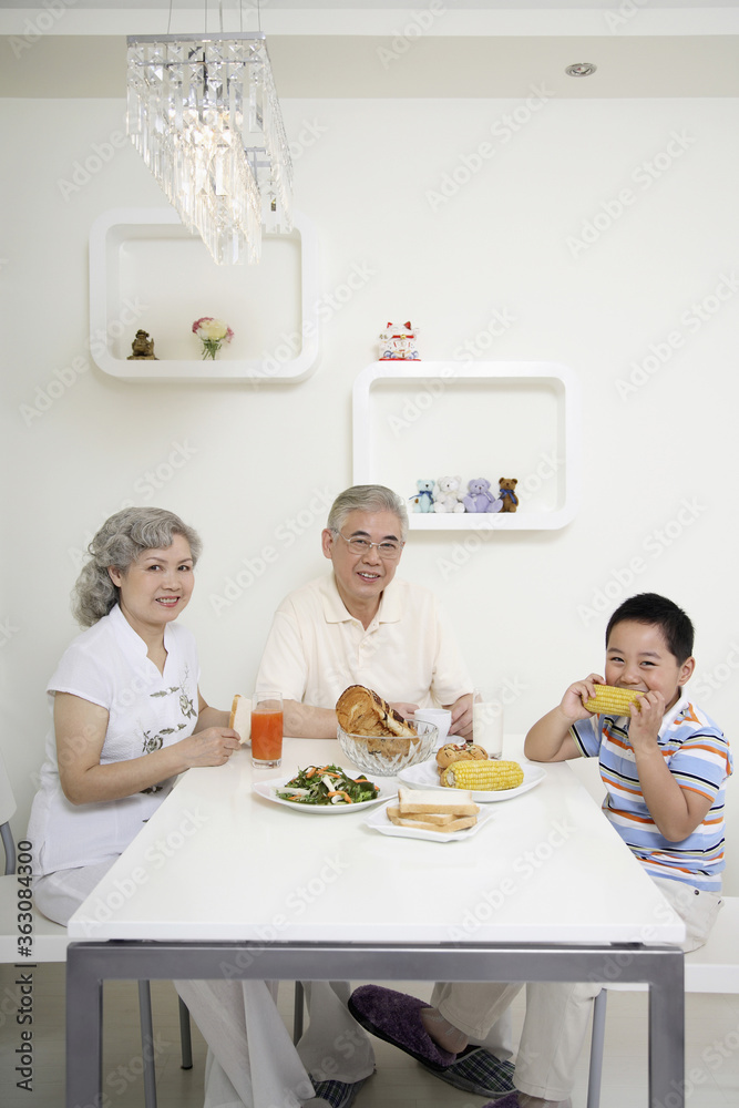 Boy having breakfast with senior man and senior woman Boy having breakfast with senior man and senior woman