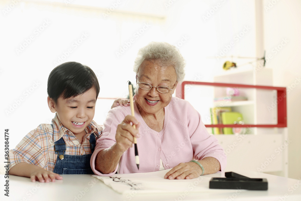 Boy observing senior woman writing calligraphy Boy observing senior woman writing calligraphy