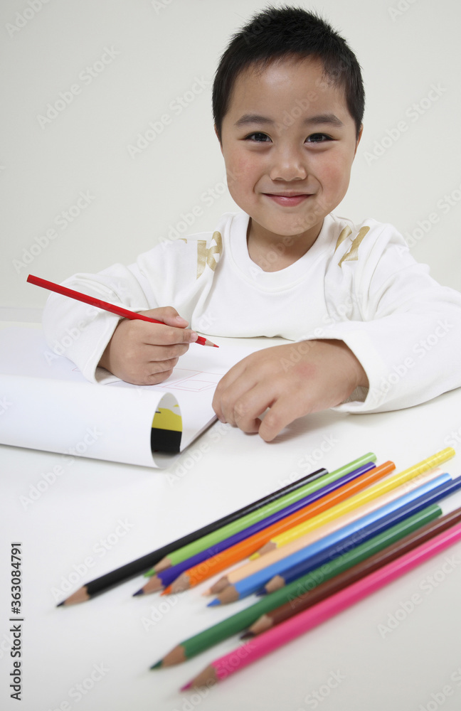 Boy smiling while holding coloured pencil Boy smiling while holding coloured pencil
