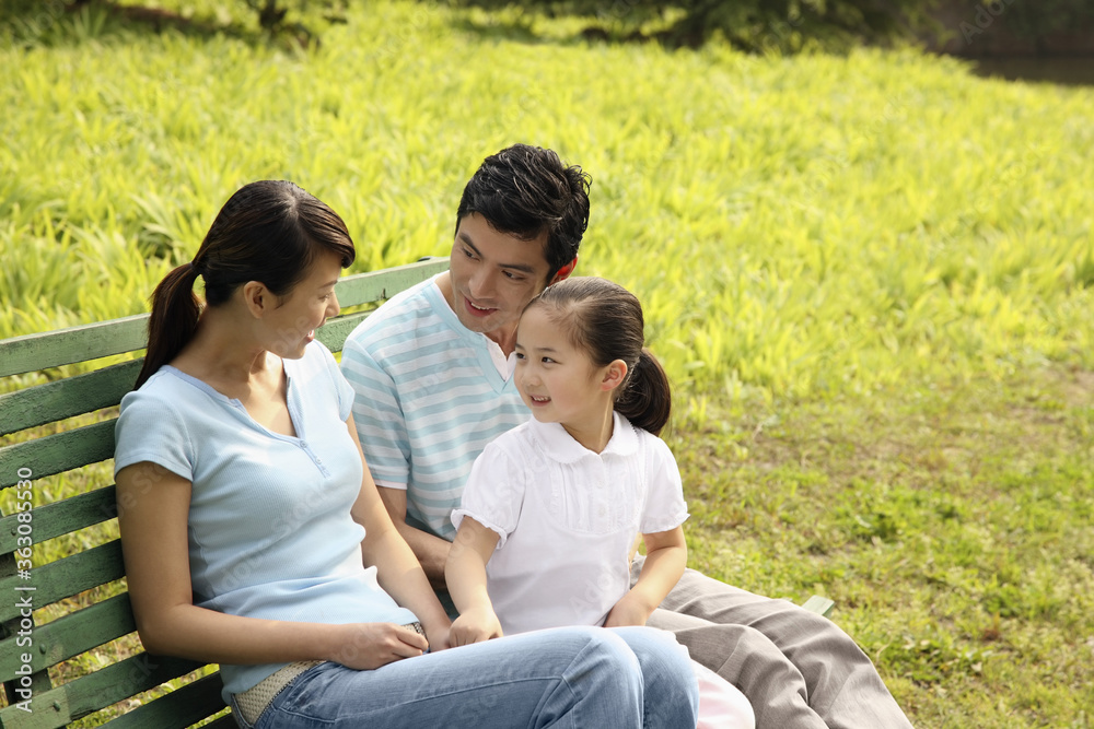 Girl chatting with parents while sitting on the bench