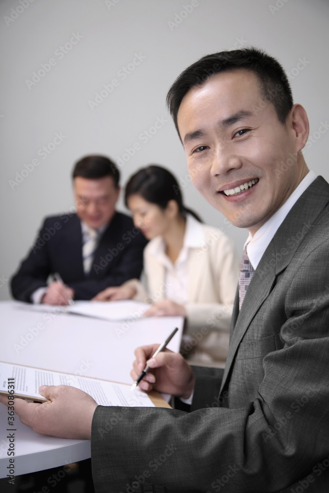 Businessman holding document, smiling at the camera Businessman holding document, smiling at the camera