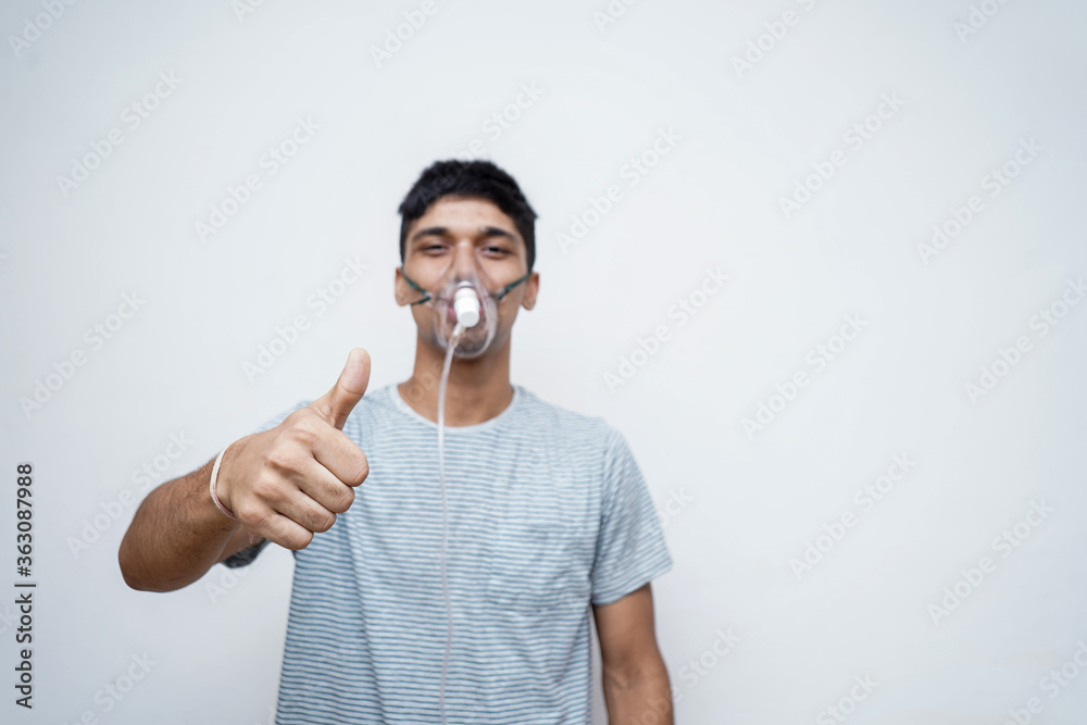 Young Handsome asian boy showing thumbs up in the camera with an oxygen mask on his face. Young Handsome asian boy showing thumbs up in the camera with an oxygen mask on his face.