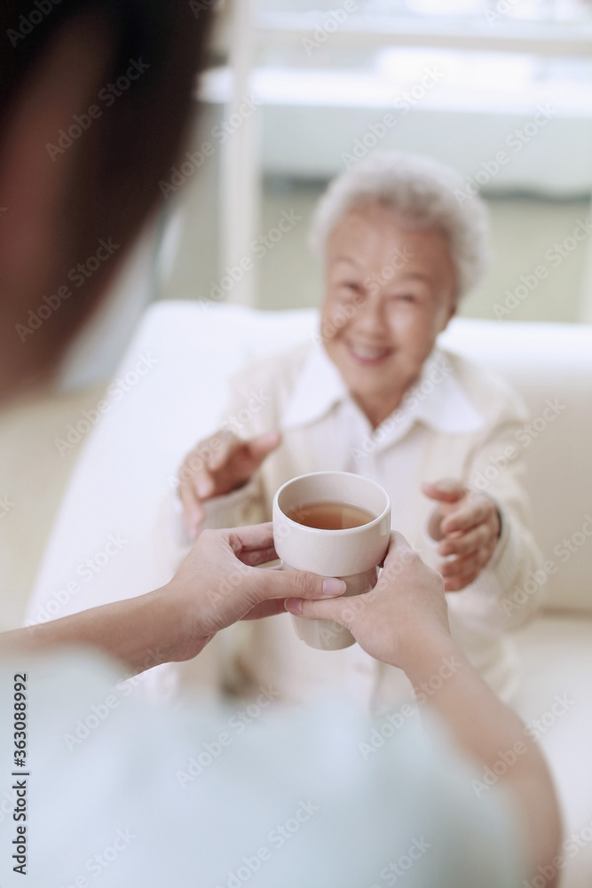 Woman serving senior woman with a cup of tea Woman serving senior woman with a cup of tea