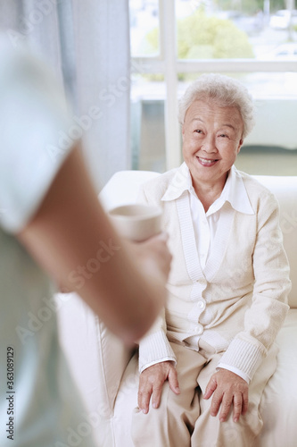 Woman serving senior woman with a cup of tea