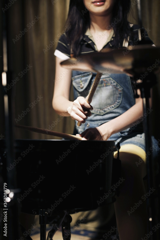 Fototapeta premium Young woman playing drums