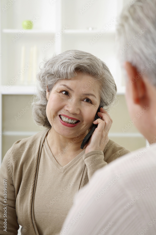 Senior woman talking on the phone, senior man watching Senior woman talking on the phone, senior man watching