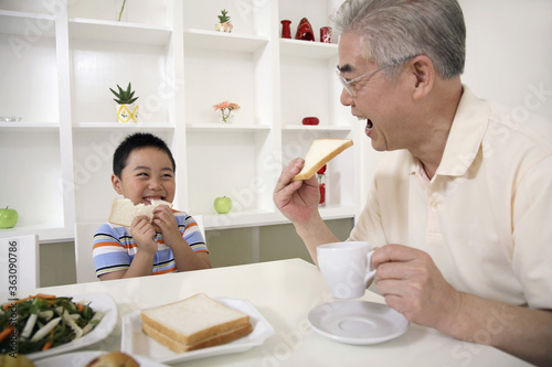 Senior man and boy eating bread