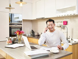 young asian business man working from home calling customer using mobile phone