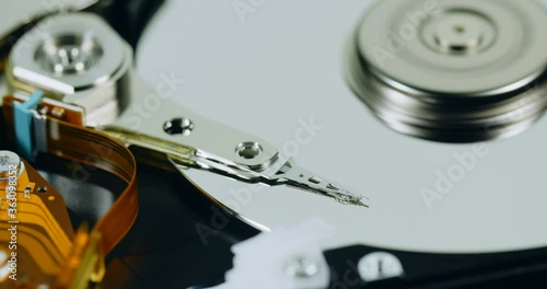 Panning closeup shot of a hard disk reading head moving over a spinning platter.