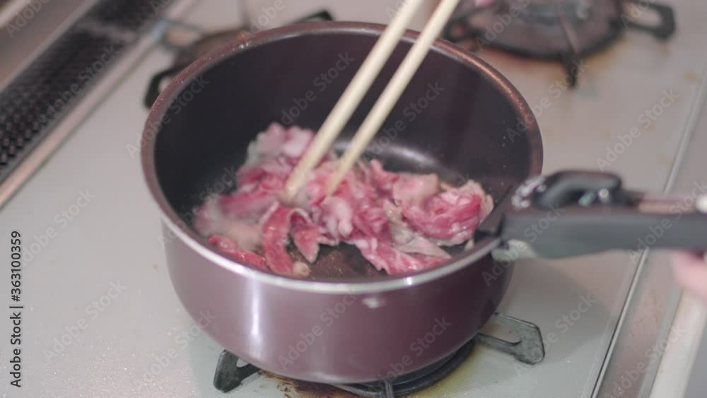Stir-Frying Meat In A Sauce Pan Using Chopsticks - close up Stir-Frying Meat In A Sauce Pan Using Chopsticks - close up