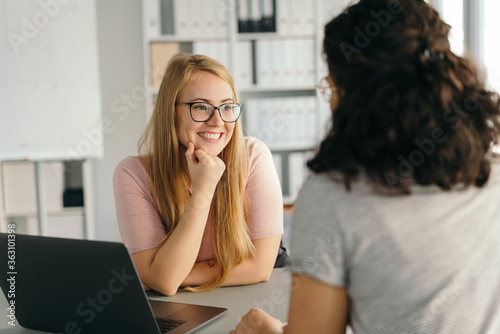 Young woman listening to a colleague with a smile photo
