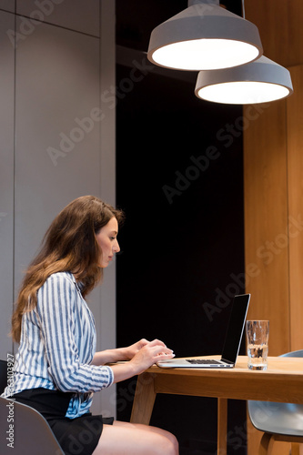 Concentrated lady using laptop for work at office