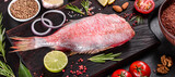 Raw fillet of red sea perch prepared for baking with spices and herbs