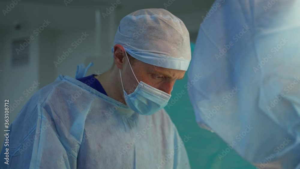 Doctor in medical mask and cap. Operating procedure by medical specialists in hospital. Professional surgeons perform operation. Healthcare concept. Doctor in medical mask and cap. Operating procedure by medical specialists in hospital. Professional surgeons perform operation. Healthcare concept.