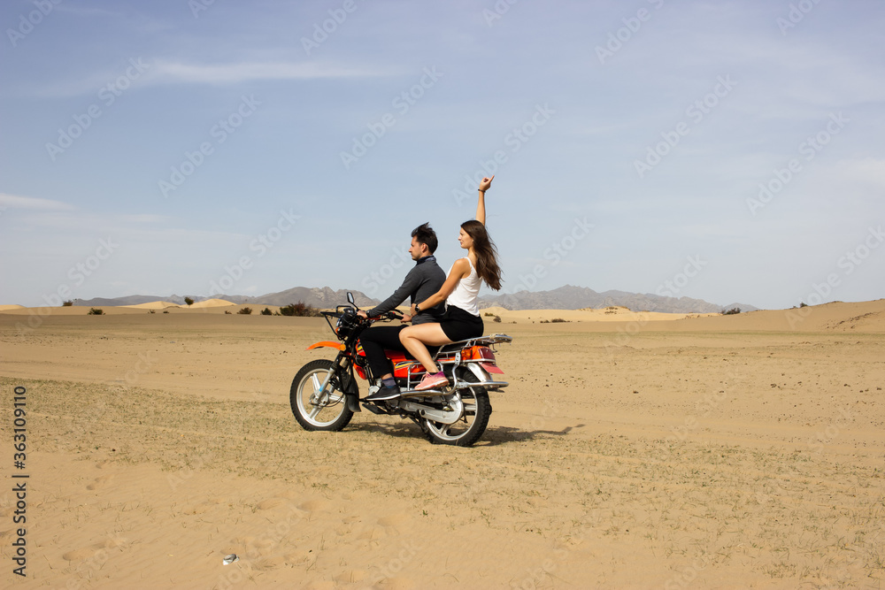 Couple driving motorbike in sand dunes of desert Gobi in Mongolia Couple driving motorbike in sand dunes of desert Gobi in Mongolia
