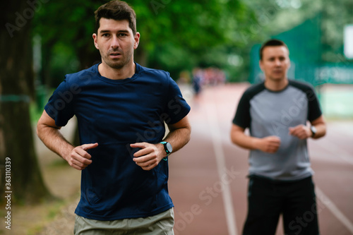 Young men training on a race track. Two young friends running on the athletics track 