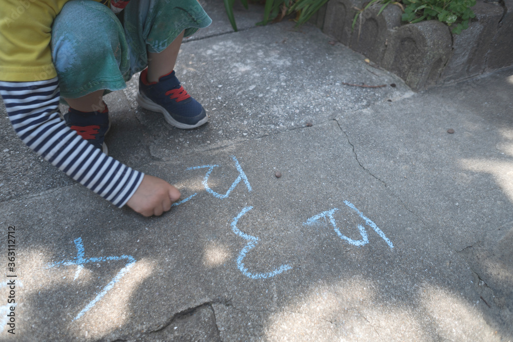 Small kid writing numbers with chalk.