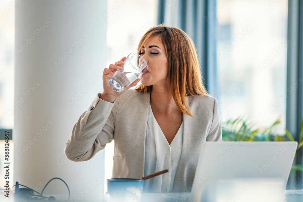 Office worker drinking water working on line. Young businesswoman drinking water in office. Happy beautiful young woman drinking water. Smiling female model holding transparent glass in her hand. Office worker drinking water working on line. Young businesswoman drinking water in office. Happy beautiful young woman drinking water. Smiling female model holding transparent glass in her hand.