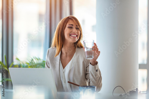 Papier peint Businesswoman drinking water while working in her office