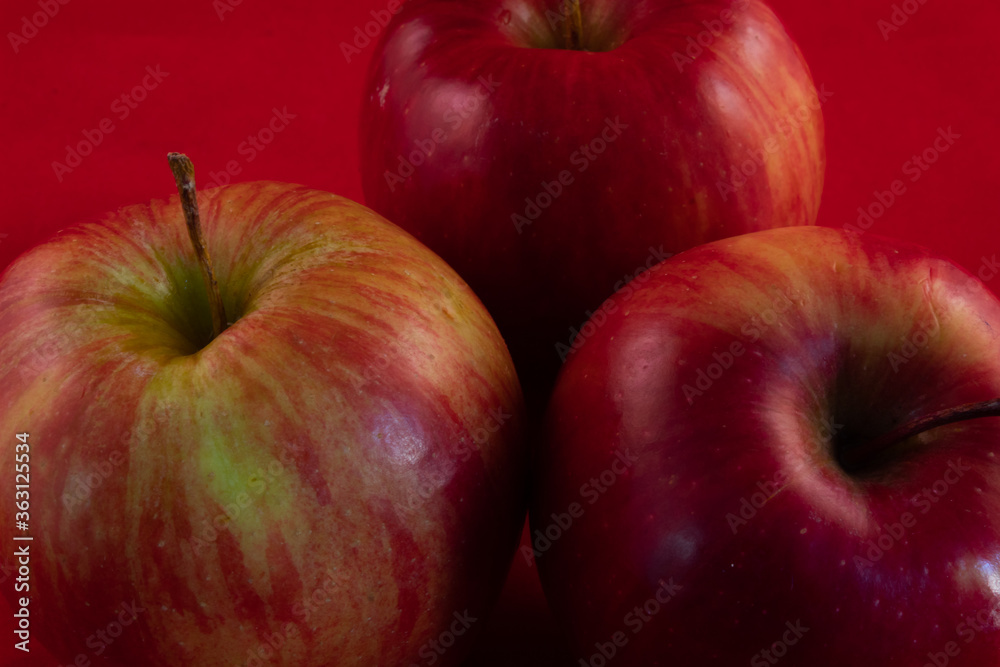 close up of many delicious shiny apple on a red studio background close up of many delicious shiny apple on a red studio background