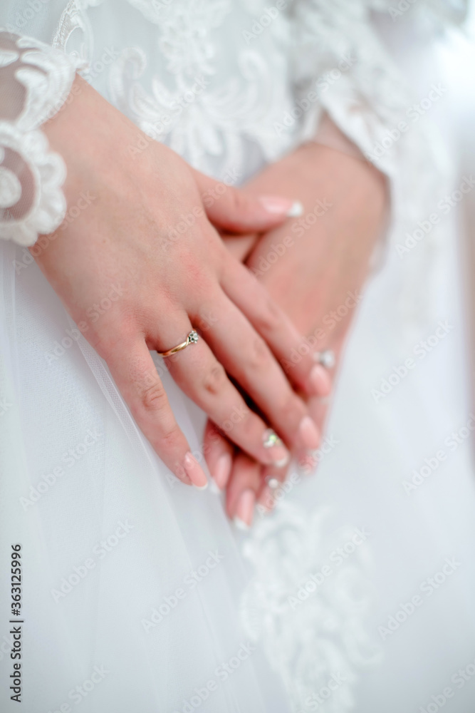 The bride holds her hands on a white wedding dres The bride holds her hands on a white wedding dres