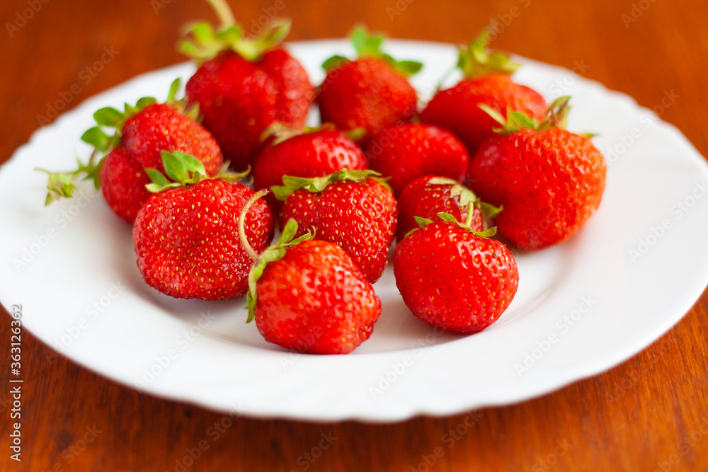 Strawberries on a white plate on a wooden table Strawberries on a white plate on a wooden table