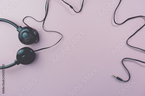 Top view of black headphones on white or pastel color background.
