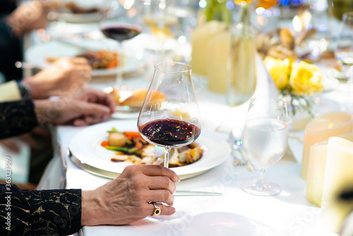 Fine dinning guest hold red wine glass on his hand