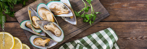 Kiwi mussels on a serving Board on a brown wooden table. Lots of kiwi mussels on a wooden serving Board. Banner