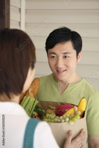 Woman taking grocery bag from man