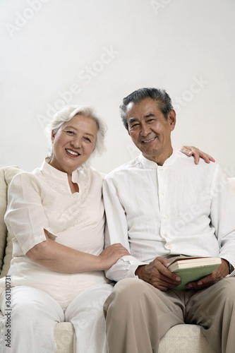 Senior couple sitting on the couch, smiling at the camera © ImageHit