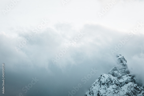 Top of a snow covered mountain, wrapped in fog and clouds