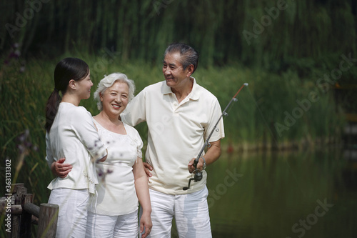 Senior man talking to senior woman and woman while fishing on a dock