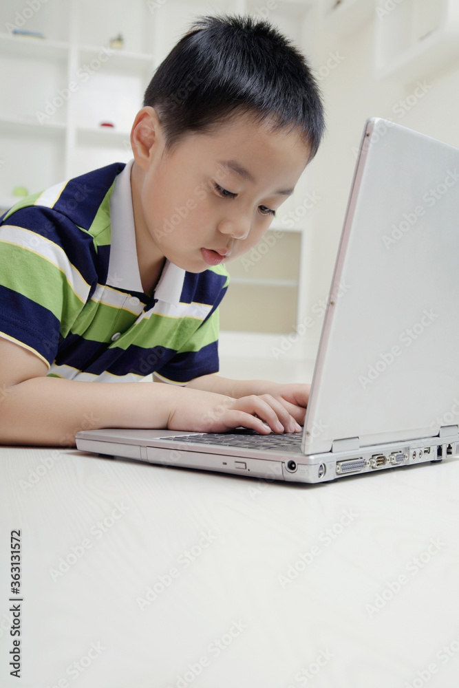 Boy lying forward on the floor using laptop Boy lying forward on the floor using laptop