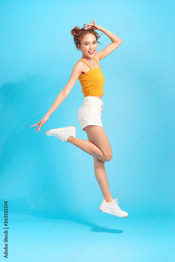 Full length of attractive casual trendy girl having fun jumping isolated over blue background