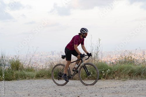 Fototapeta Naklejka Na Ścianę i Meble -  Cyclist man pedaling standing with his gravel bike with the city of Barcelona on the horizon