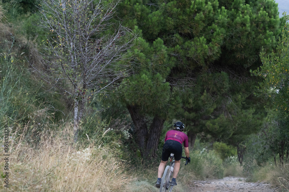 Cyclist man going down a trail with a gravel bike