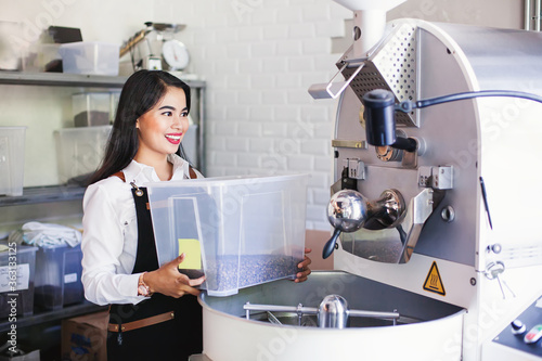 Beautiful asian woman taking coffee for roasting in a roastery