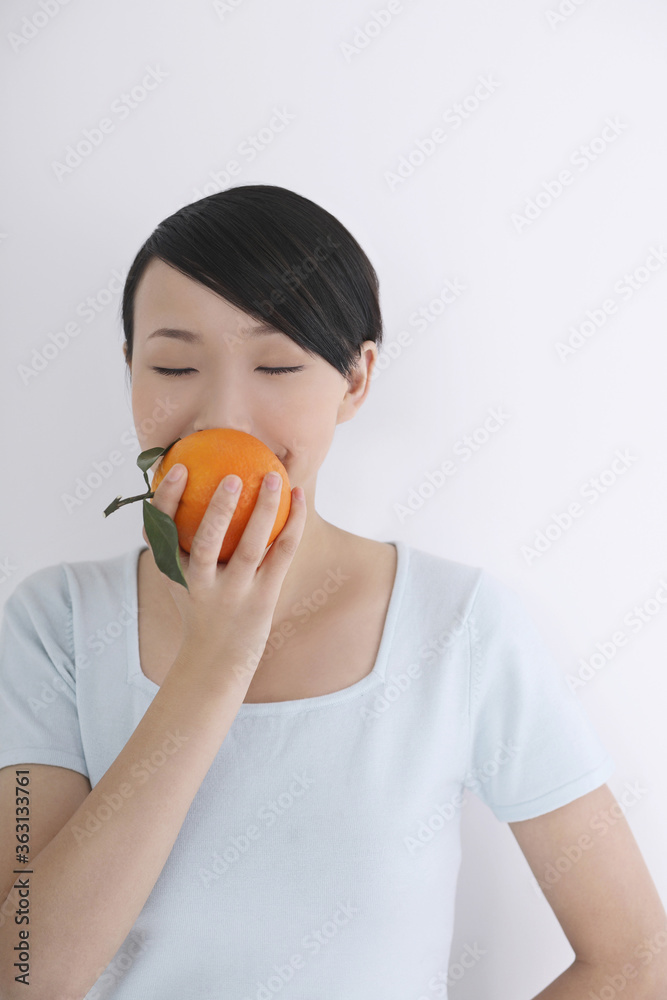 Woman smelling orange with her eyes closed Woman smelling orange with her eyes closed
