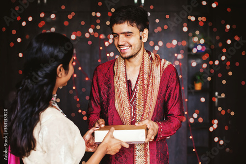 Handsome Indian man in traditional festive ethnic clothes giving a gift to a woman photo