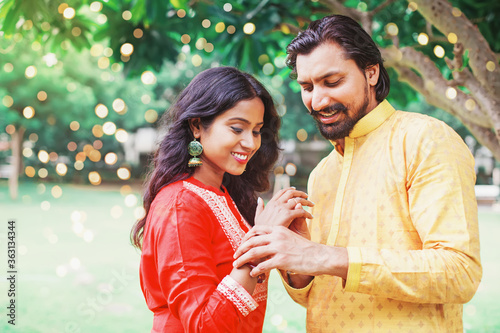 Indian engagement: Young man putting diamond ring on his bride's finger
