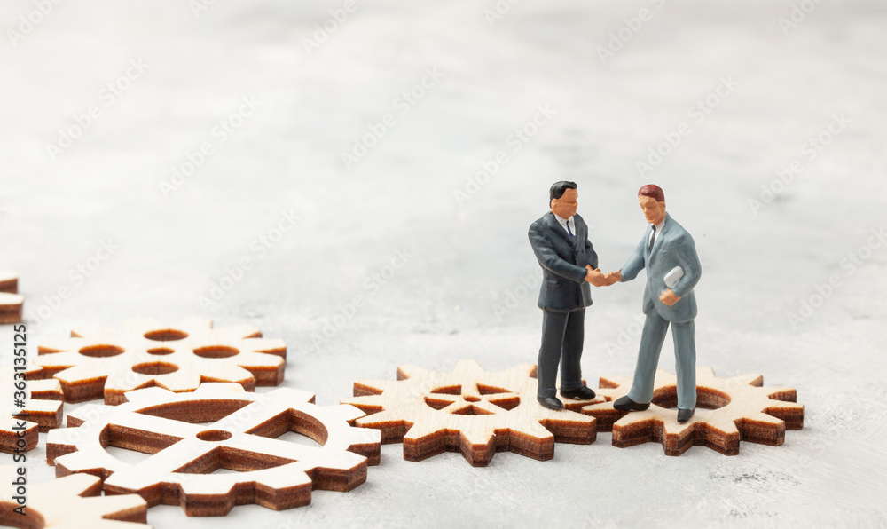 Hiring staff. Selection of the leader of the manager for the company. Businessmen in suits shake hands on gears as a symbol of business processes in the company Hiring staff. Selection of the leader of the manager for the company. Businessmen in suits shake hands on gears as a symbol of business processes in the company