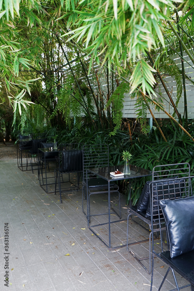 Fototapeta premium Exterior design and restaurant decoration of outdoor dining seats decorated with metal furniture in green bamboo garden park