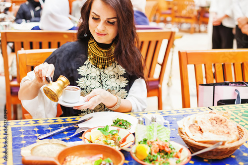 Young caucasian woman traveling in Turkey, drinking turkish coffee and eating traditional food in a outdoor cafe photo