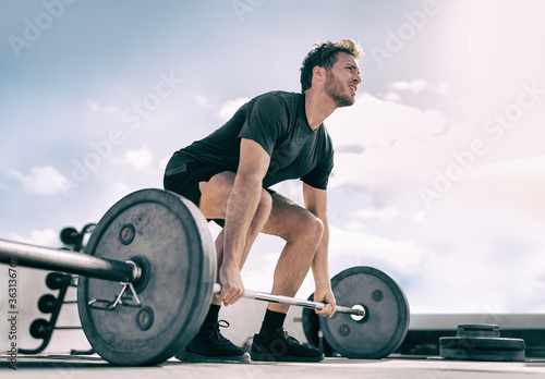 Gym fitness weightlifting deadlift man bodybuilding powerlifting at outdoor summer health club. Bodybuilder doing barbell weight lifting training workout with heavy bar. photo