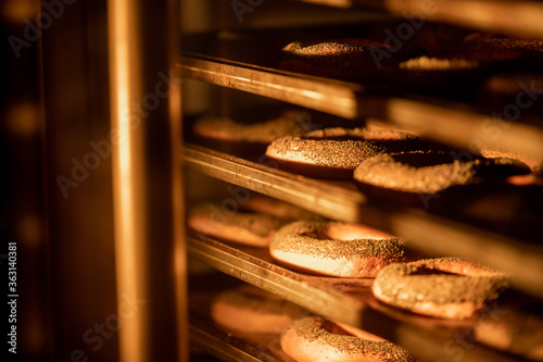 Bagels with poppy seeds are baked in oven. Industrial food production line